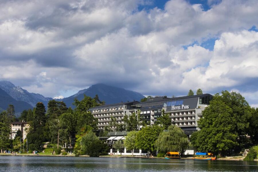 Scenic view of Lake Bled with the elegant exterior of Hotel Park in the foreground, surrounded by lush greenery