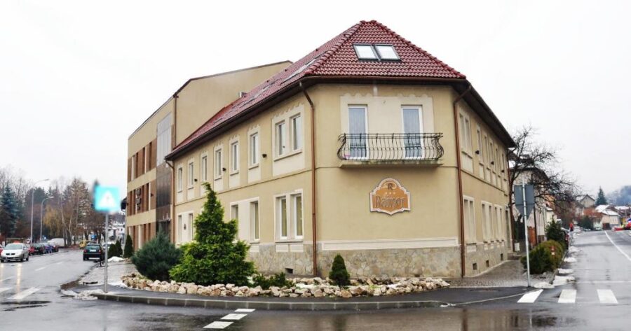 Hotel Rainer in Brasov, distinguished by its red roof and balcony, surrounded by scenic landscapes.