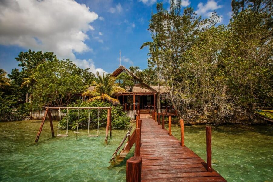 Scenic wooden dock leads to a house on the water at Hotel Rancho Encantado, Bacalar, Quintana Roo, Mexico.