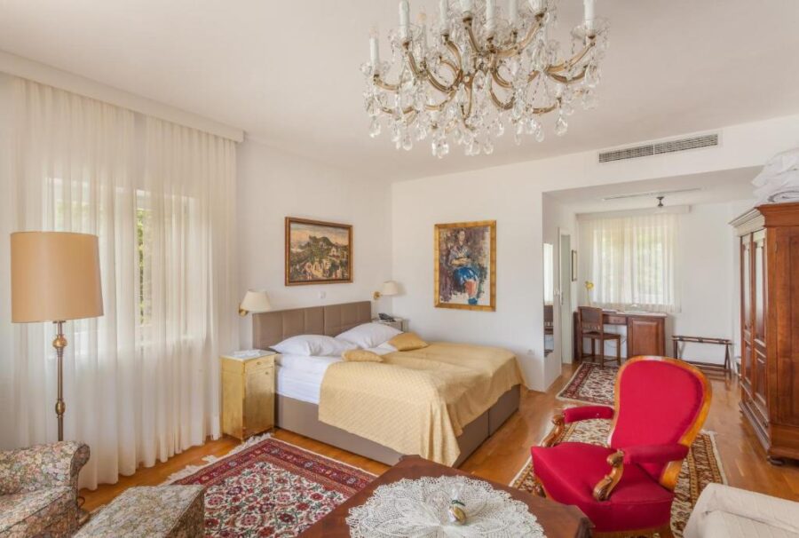 Cozy bedroom at Hotel Triglav featuring a bed, chair, and table, perfect for relaxation and comfort.