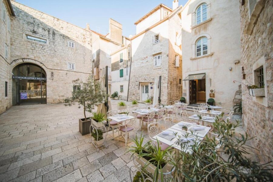 Courtyard of Hotel Vestibul Palace & Villa in Split, Croatia, featuring tables and chairs surrounded by old stone walls.