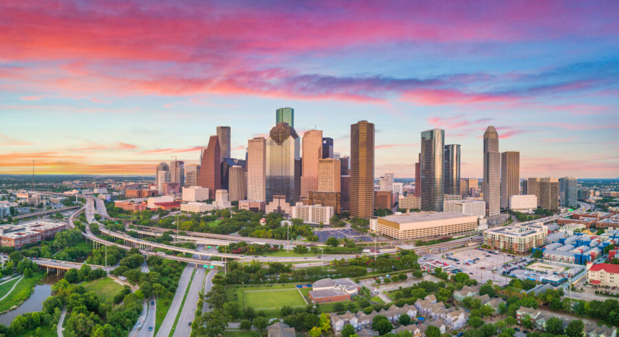 Aerial panorama of downtown Houston, Texas, showcasing the skyline with modern skyscrapers against a clear blue sky.