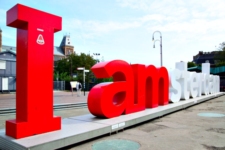 Close-up of the "I Amsterdam" sign, showcasing bold letters against a blurred background of the cityscape.