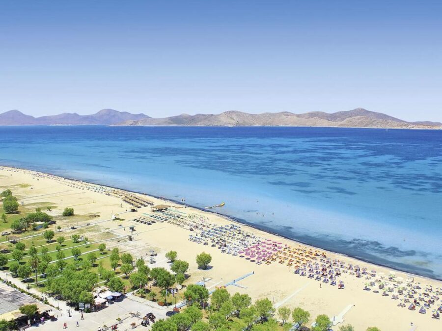 Tigaki Beach, Kos, Greece — long sandy shore with turquoise waters and colorful umbrellas.