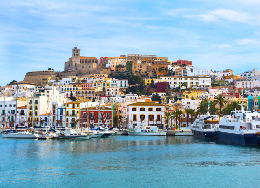Vibrant buildings of Ibiza Old Town overlook the port, showcasing a mix of colors and Mediterranean architecture