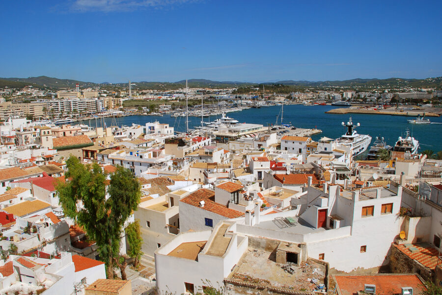 Panoramic view from the historic old town of Ibiza, showcasing the bustling port and azure waters beyond