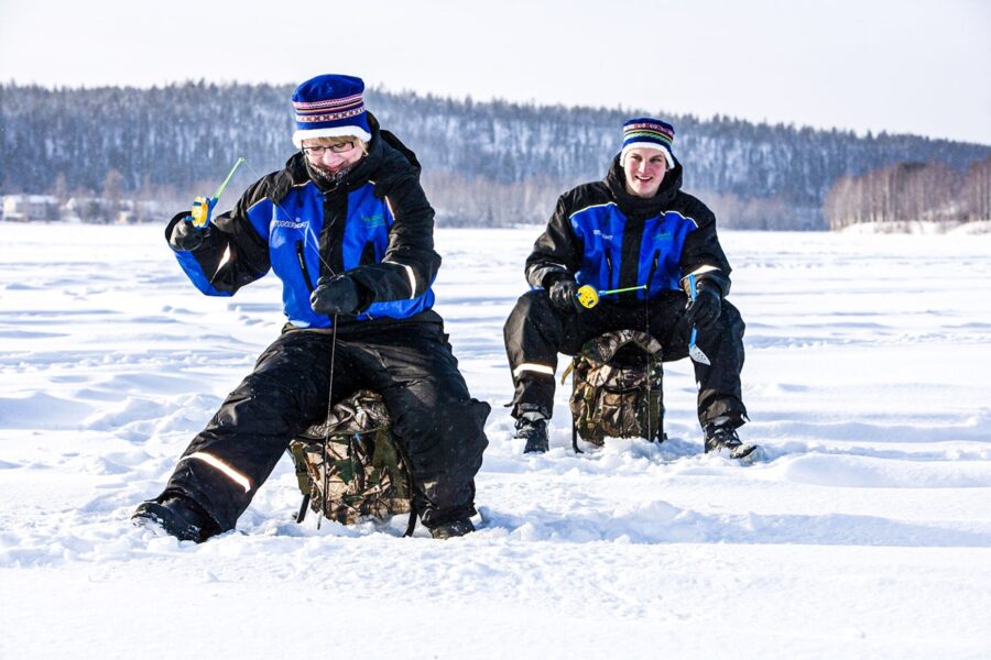 Ice fishing on a frozen lake with two men in winter gear.