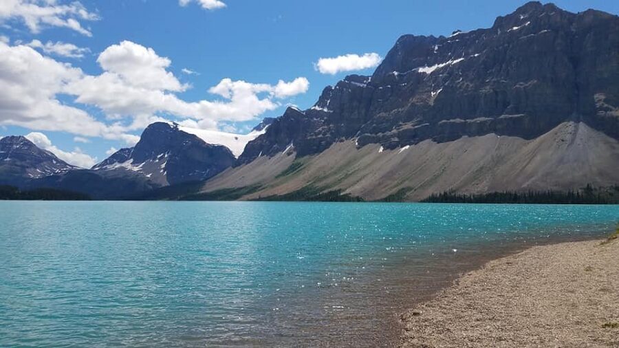 Picturesque lake with vibrant blue water and towering mountains in the background, located on the Icefields Parkway.