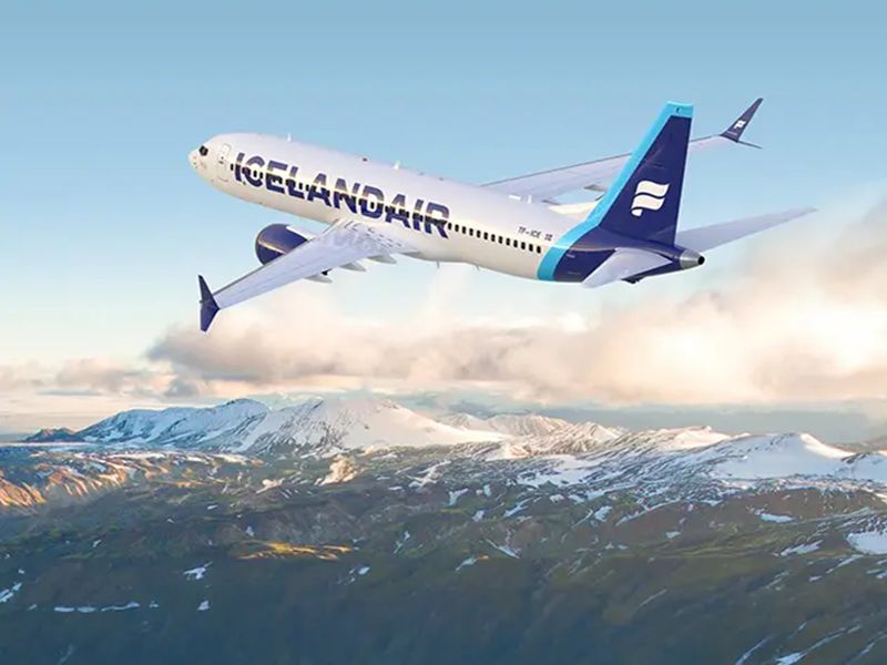 Icelandair Boeing 737 flying over snow-capped mountains and fluffy clouds, showcasing Icelands beauty.