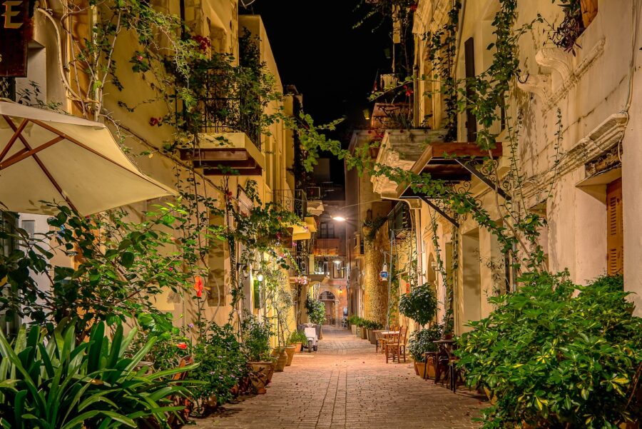 Charming illuminated Chania alley with green plants and balconies in the old town.
