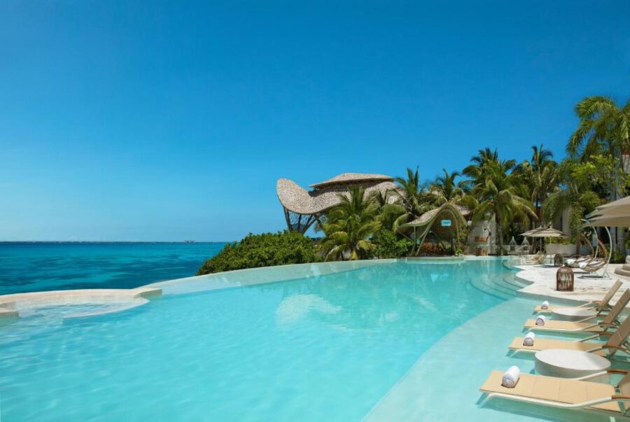 The inviting pool area of the Impression Isla Mujeres in Isla Mujeres, Mexico, with vibrant greenery and comfortable seating.