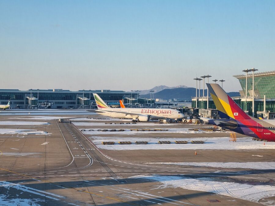 Airplanes parked on the tarmac at Incheon International Airport during winter, surrounded by a snowy landscape.