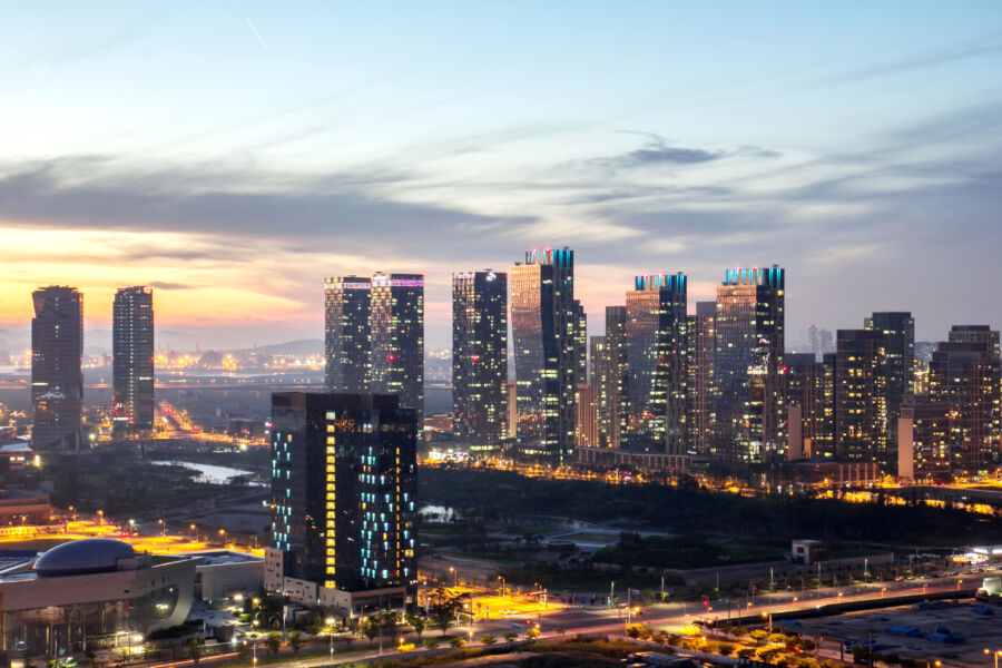 Panoramic view of Songdo, Incheon at night, featuring glowing buildings and a lively urban atmosphere