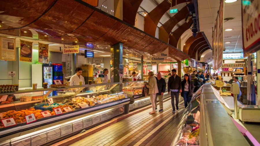 Cork English Market indoor food market aisle with chicken counter, deli displays, and shoppers.
