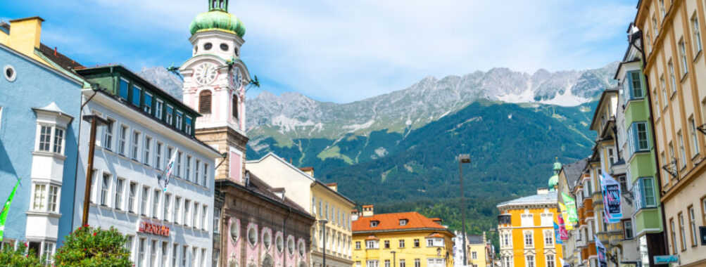 Busy Innsbruck town center filled with people enjoying street cafes against a backdrop of Tyrolean architecture.