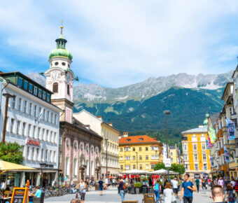 Busy Innsbruck town center filled with people enjoying street cafes against a backdrop of Tyrolean architecture.