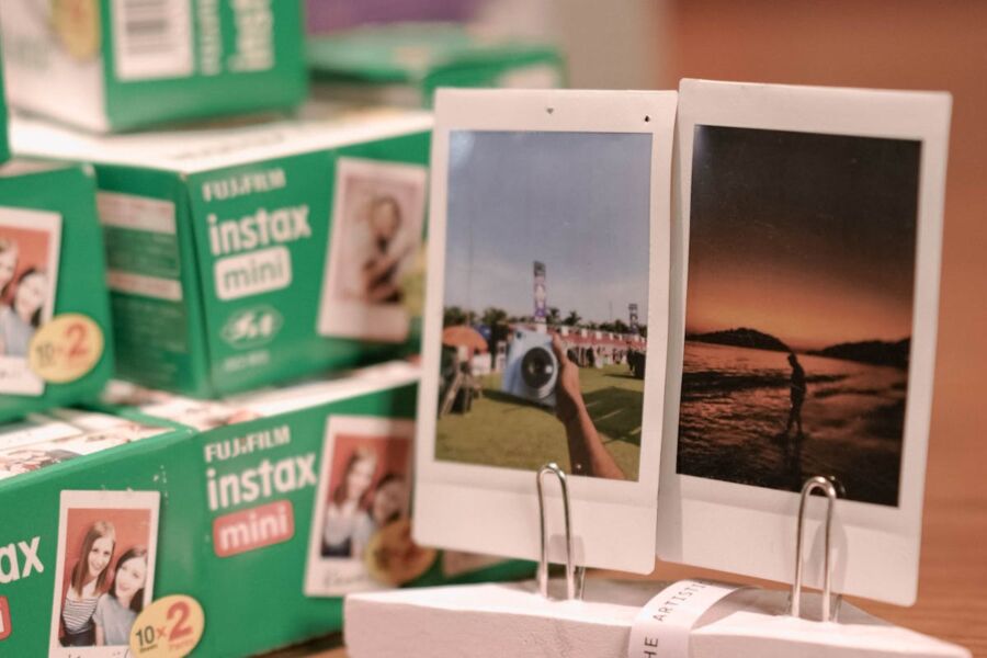 Instant film photos with Fujifilm Instax Mini boxes as backdrop in creative setting.