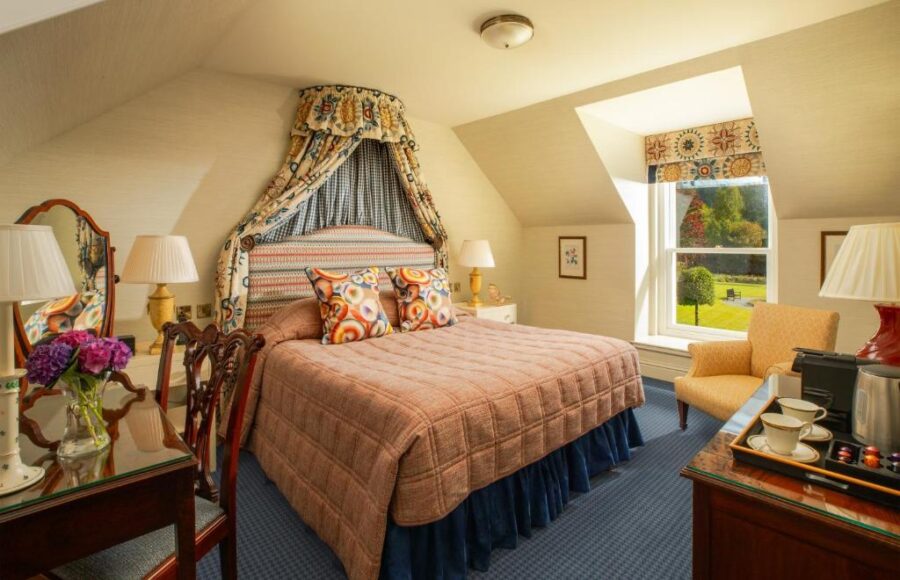 Spacious hotel room at Inverlochy Castle Hotel featuring a large bed and a window with scenic views