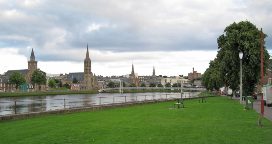Grassy area beside a river in Inverness, Scotland, showcasing a serene natural landscape.
