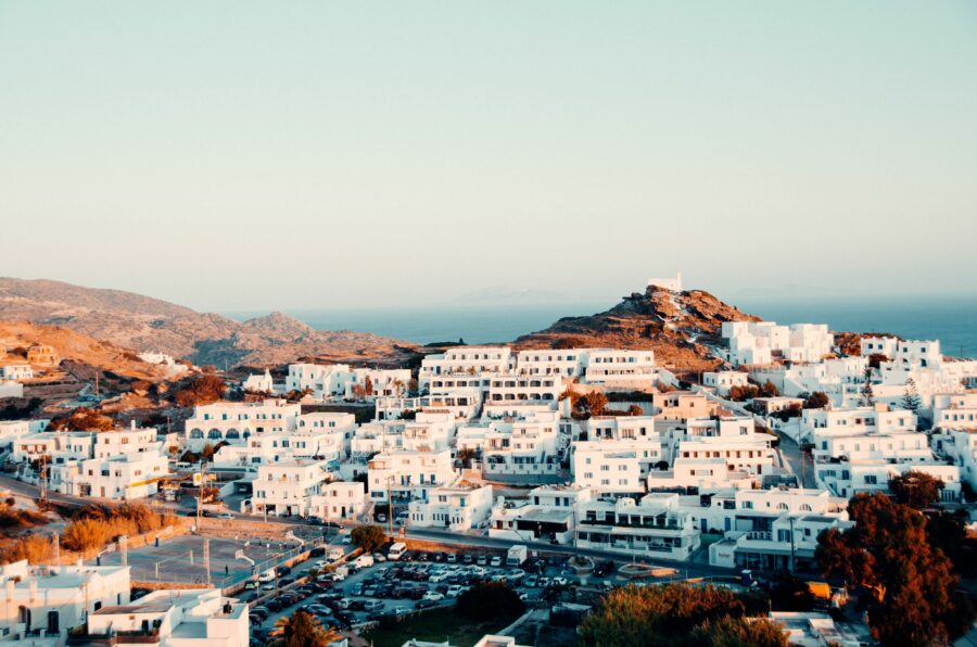 Scenic view of a village with white buildings on Ios island, Greece, surrounded by vibrant greenery and blue waters