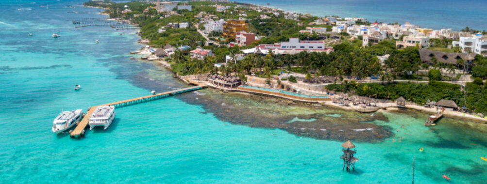 Aerial view of Isla Mujeres, Mexico, showcasing a tropical island with a dock extending into the turquoise waters.