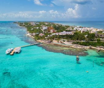 Aerial view of Isla Mujeres, Mexico, showcasing a tropical island with a dock extending into the turquoise waters.