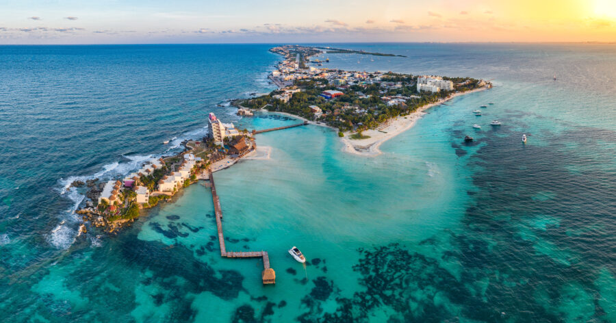 Aerial panorama of Isla Mujeres, Mexico, showcasing vibrant blue waters, sandy beaches, and lush greenery.
