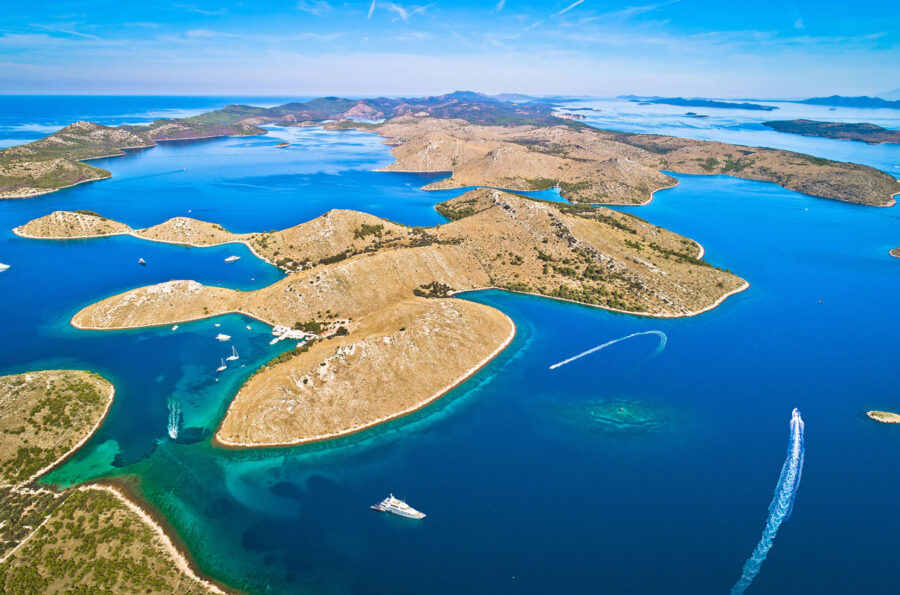 Aerial view of Kornati Islands archipelago with boats, blue waters, and lush green hills.
