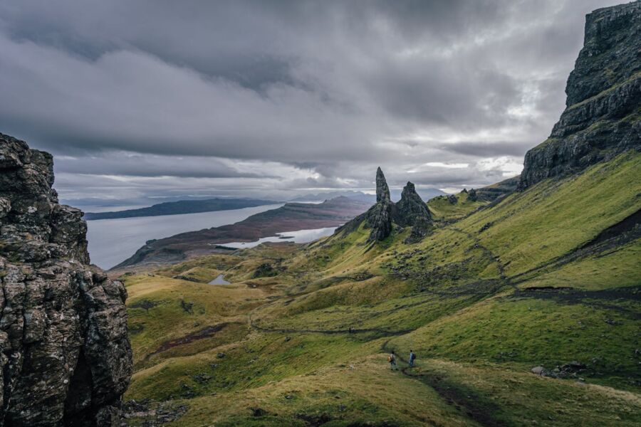 Majestic rock spires, lush greenery, and serene water on Isle of Skye hiking landscape.