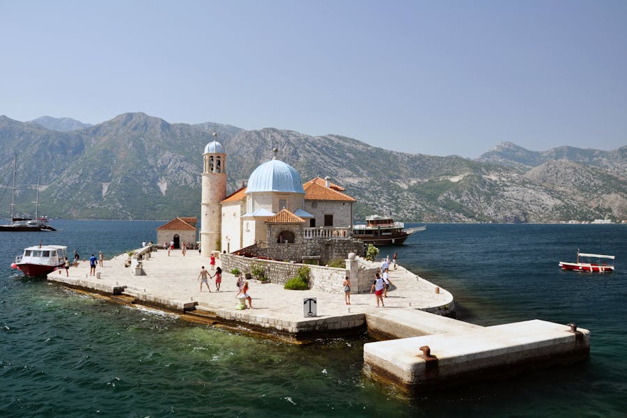 Our Lady of the Rocks church on islet in Montenegro with blue dome and pier.