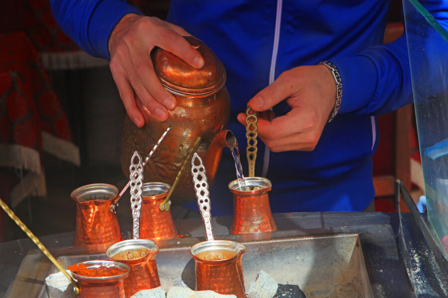 Street vendor in Istanbul prepares traditional Turkish coffee over coals with a copper pot, showcasing local culture