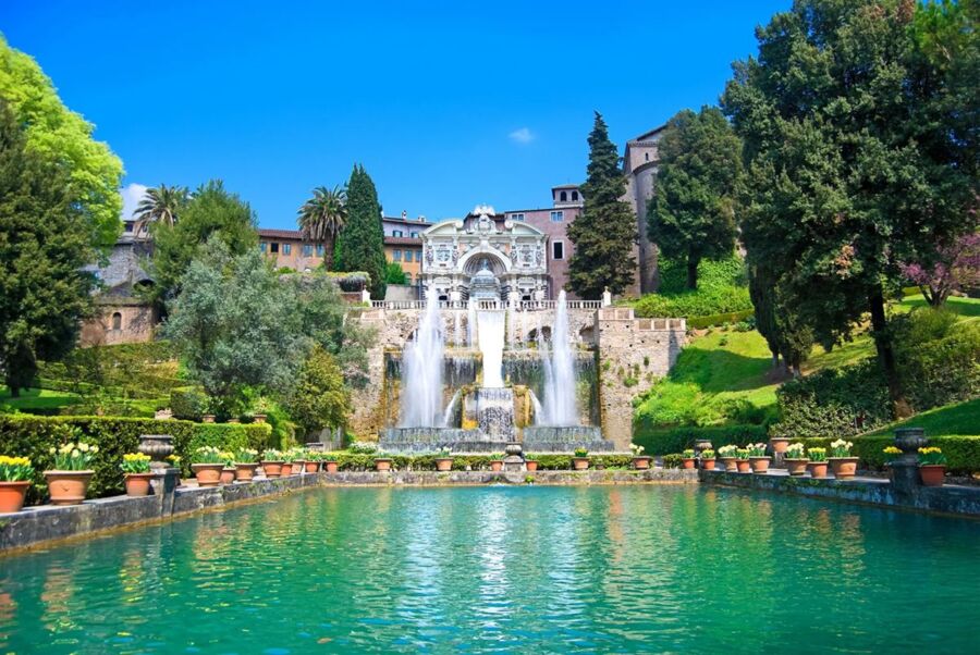 Grand fountain in lush Italian garden, Villa d’Este, showcasing historical architecture and colorful blooms.