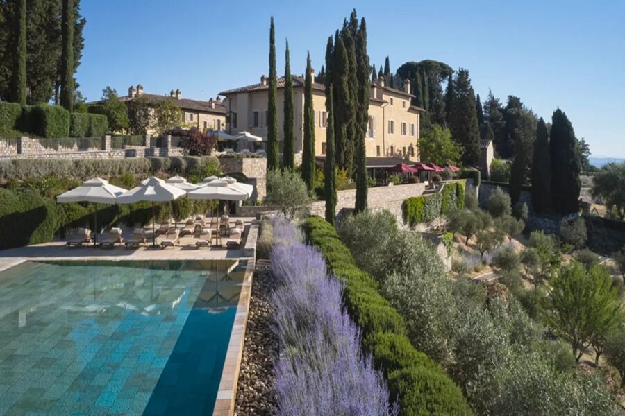 Charming Italian villa with pool, gardens, and cypress trees in picturesque countryside.