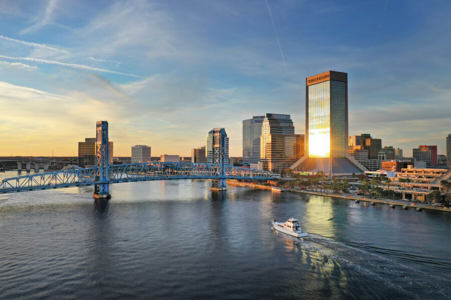 Panoramic view of Jacksonville, Florida's skyline during sunset, highlighting the city's architecture and colorful sky.