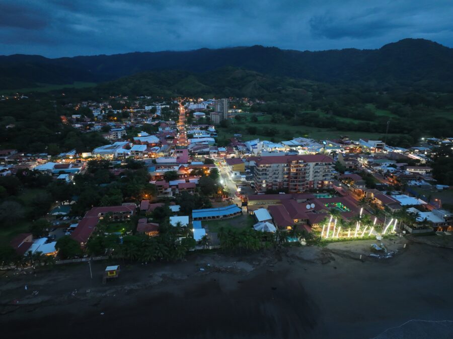 Night view of Jaco Beach, Costa Rica, featuring dark skies, gentle waves, and distant lights along the shoreline