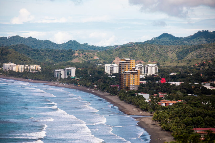 Scenic view of Jaco Beach city in Costa Rica, featuring sandy shores, ocean waves, and colorful beachfront structures