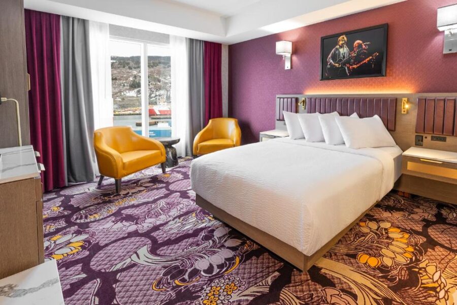 Hotel room at JAG Boutique Hotel in St. John's, Canada, featuring purple walls and a neatly made bed.