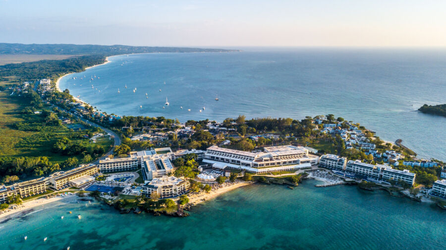 Aerial view of Negril, Jamaica, showcasing a stunning Caribbean beach with golden sand and a vibrant sunset over the ocean