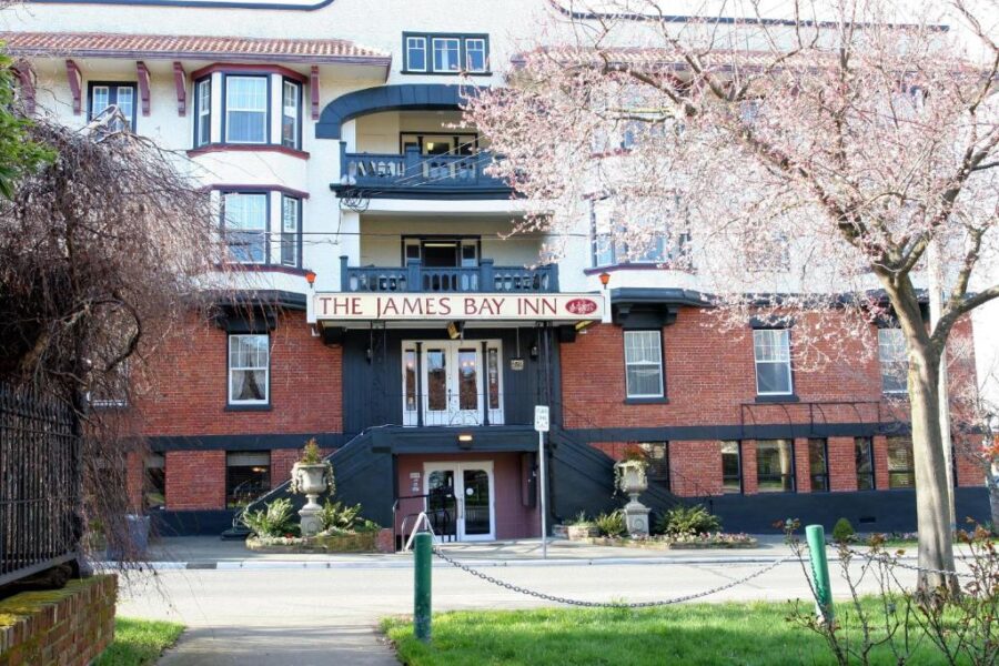 James Bay Inn Hotel, Suites & Cottage at the street corner in Victoria, Canada, showcasing its welcoming exterior.