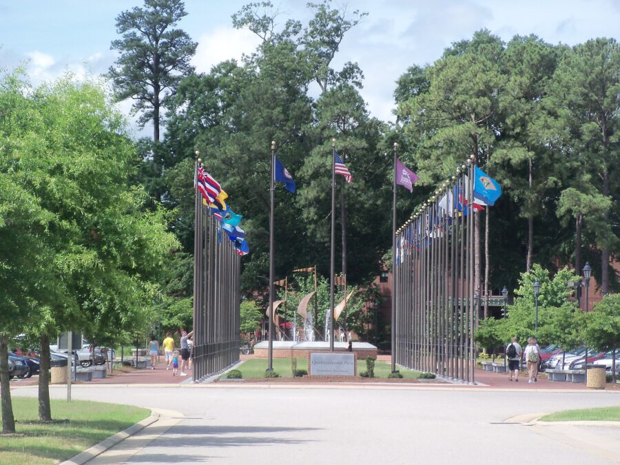Scenic view of a park in Jamestown Settlement, Virginia, showcasing lush trees and a significant monument.