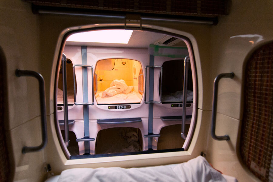 Inside a Japan capsule hotel, a bed is adorned with a teddy bear resting comfortably on the sheets.
