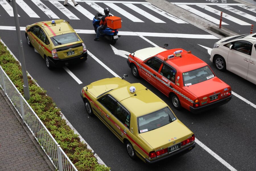 Japanese taxis in various colors driving along a bustling city street