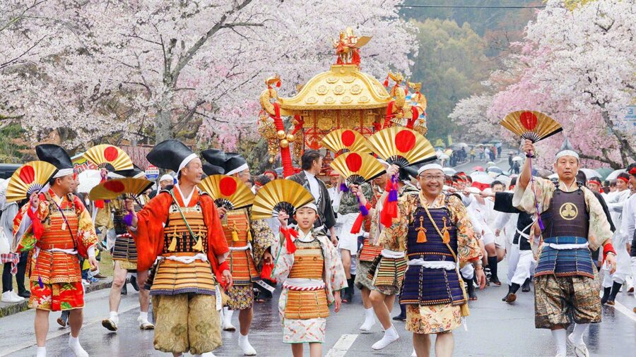 Japanese festival with cherry blossoms, traditional attire, joyous parade, and colorful mikoshi shrine.
