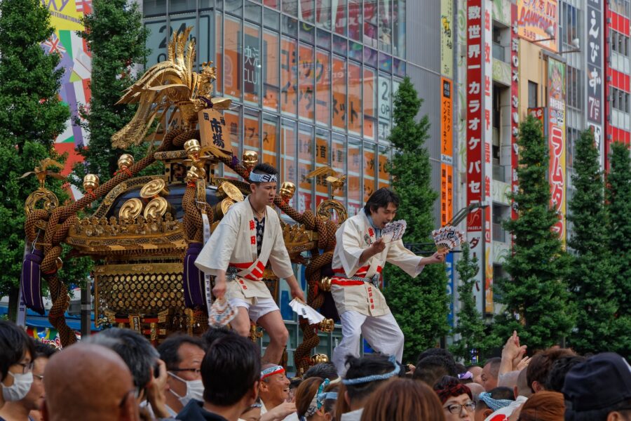 Japanese festival celebrating culture with mikoshi parade, traditional attire, and vibrant crowd.