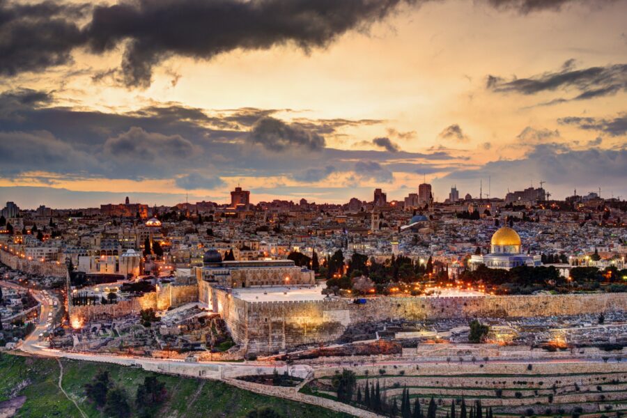 Jerusalem panorama at dusk with Dome of the Rock, ancient architecture, and vibrant sky.