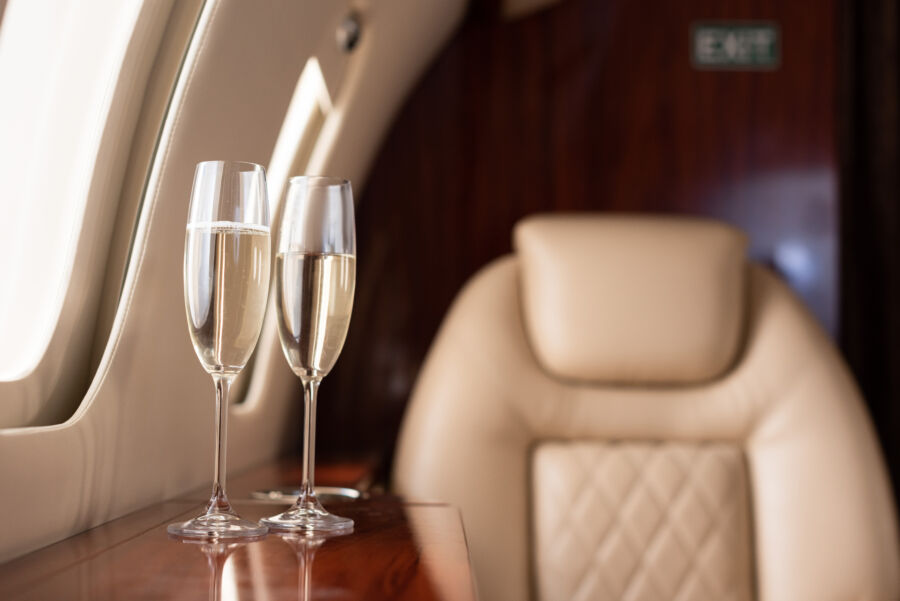 Interior of a jet plane featuring a luxurious seat and two champagne glasses elegantly placed on a table