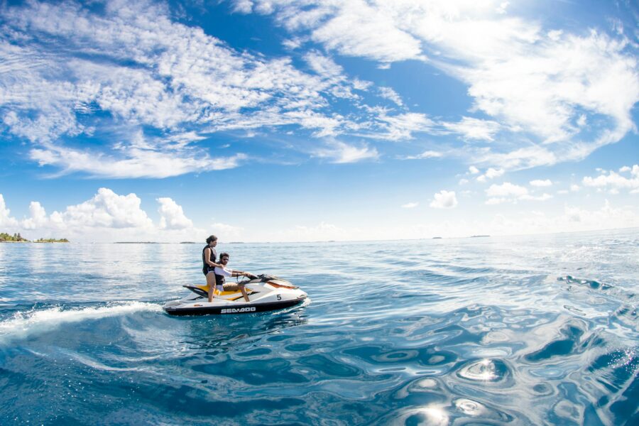 Jet ski adventure on clear blue ocean with sunny sky and distant island backdrop.