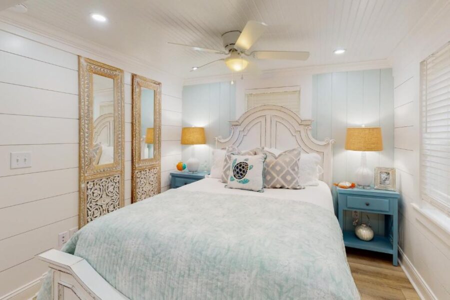 Cozy bedroom featuring a white bed with blue accents, located in Jewel's Cottage, Jekyll Island, Georgia.