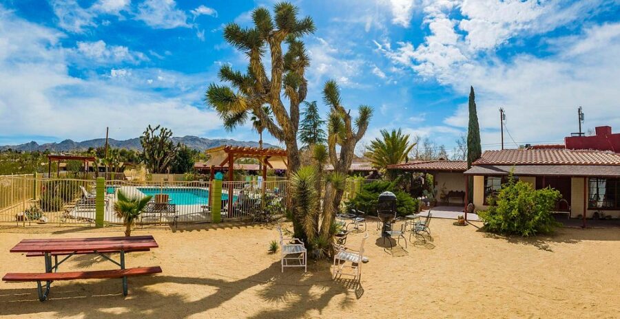 Scenic view of a picnic table next to a pool in a desert setting at Joshua Tree Inn, highlighting the arid environment.