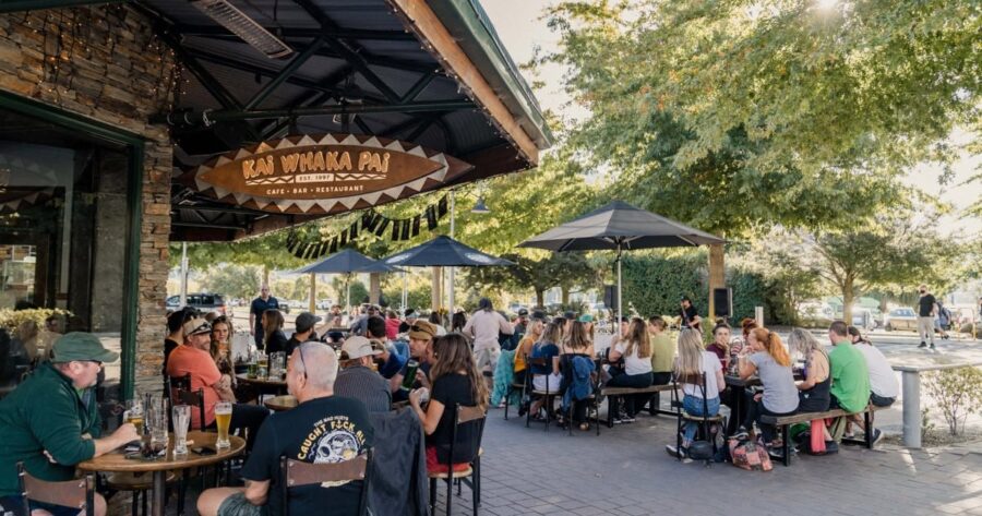 Outdoor dining at Kai Whaka Pai café bar restaurant with people drinking, socializing, and enjoying sunshine.